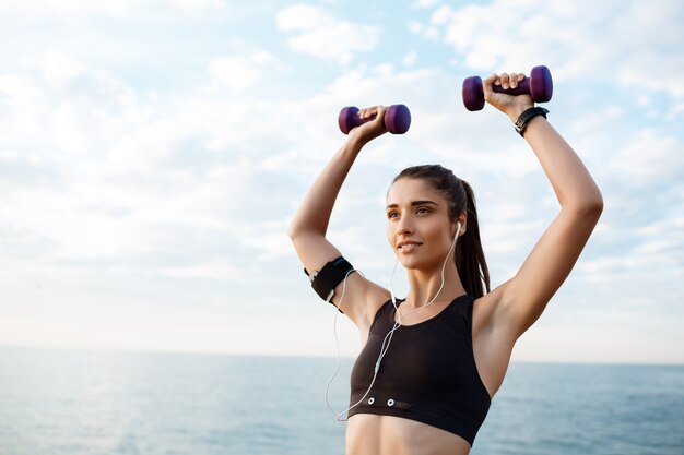 Joven hermosa niña deportiva entrenamiento al amanecer sobre el mar.