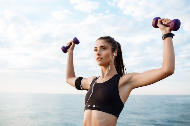 Joven hermosa niña deportiva entrenamiento al amanecer sobre el mar.