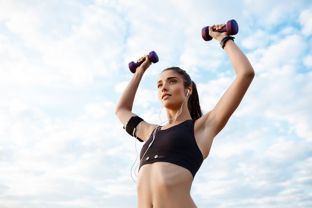 Joven hermosa niña deportiva entrenamiento al amanecer sobre el mar.