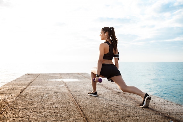 Foto gratuita joven hermosa niña deportiva entrenamiento al amanecer sobre el mar.