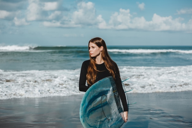 joven hermosa niña posando en la playa con una tabla de surf, surfista mujer, olas del océano