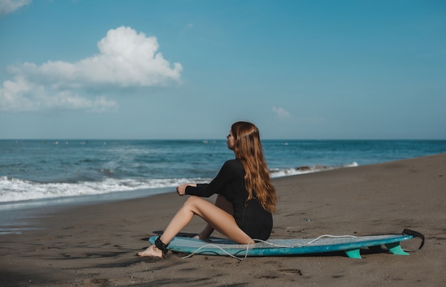 joven hermosa niña posando en la playa con una tabla de surf, surfista mujer, olas del océano