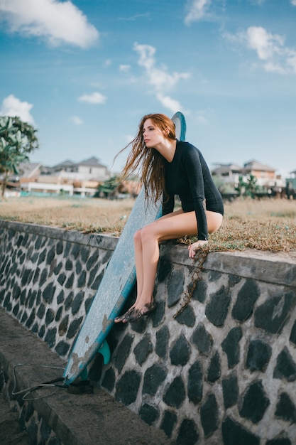 joven hermosa niña posando en la playa con una tabla de surf, surfista mujer, olas del océano