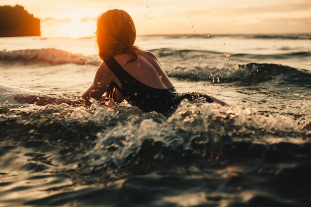 joven hermosa niña posando en la playa con una tabla de surf, surfista mujer, olas del océano