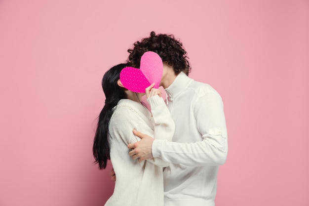 Joven, hermosa pareja de enamorados en la pared rosada del estudio