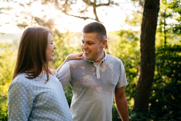 joven hermosa pareja feliz en el amor caminando juntos en la hierba y el parque de árboles paisaje