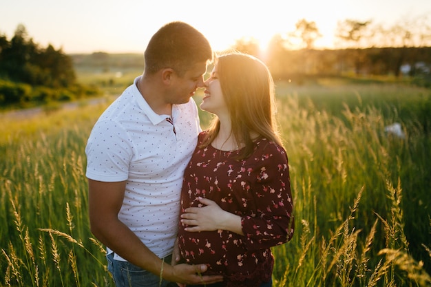 joven hermosa pareja feliz en el amor caminando juntos en la hierba y el parque de árboles paisaje