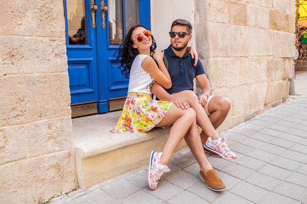 Joven hermosa pareja de hipster enamorados sentados en la calle de la ciudad vieja