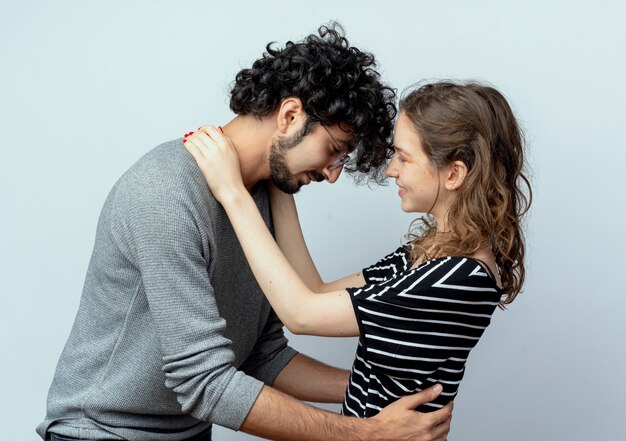 Joven hermosa pareja hombre y mujer felices enamorados abrazándose unos a otros sobre fondo blanco.