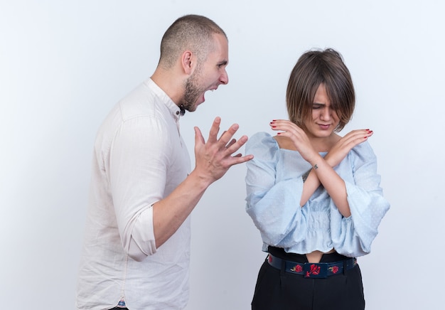 Foto gratuita joven hermosa pareja en ropa casual hombre y mujer peleando hombre gritando a su novia confundida estanding sobre pared blanca