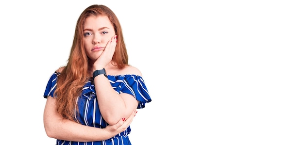 Joven hermosa pelirroja con ropa informal pensando que parece cansada y aburrida con problemas de depresión con los brazos cruzados.