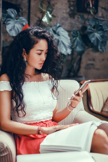 Joven hermosa usa un teléfono inteligente en la calle, navegando por internet