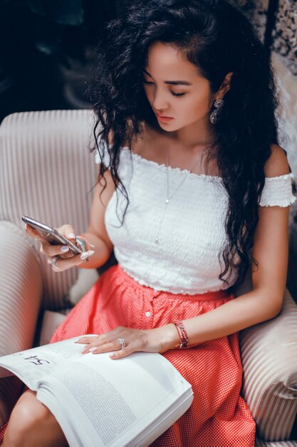 Joven hermosa usa un teléfono inteligente en la calle, navegando por internet