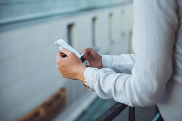 Joven hermosa usa un teléfono inteligente en la calle, navegando en internet