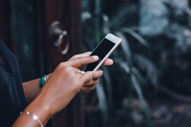 Joven hermosa usa un teléfono inteligente en la calle, navegando por internet