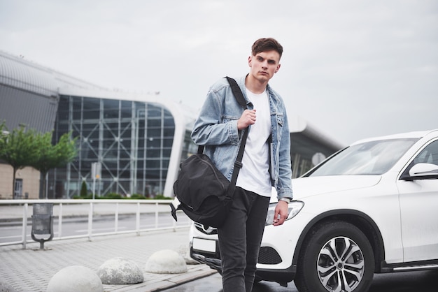 Un joven hermoso en el aeropuerto está esperando el vuelo.