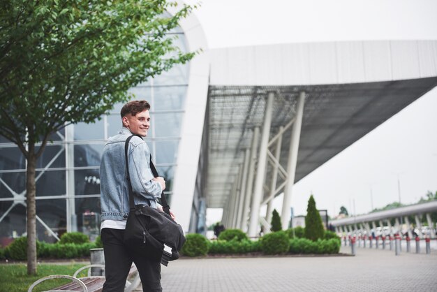 Un joven hermoso en el aeropuerto está esperando el vuelo.