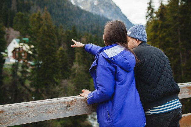 Joven hipster hermosa pareja de enamorados, en el bosque de invierno, vacaciones de invierno en las montañas