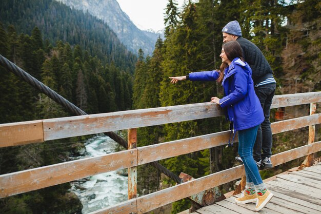 Joven hipster hermosa pareja de enamorados, en el bosque de invierno, vacaciones de invierno en las montañas