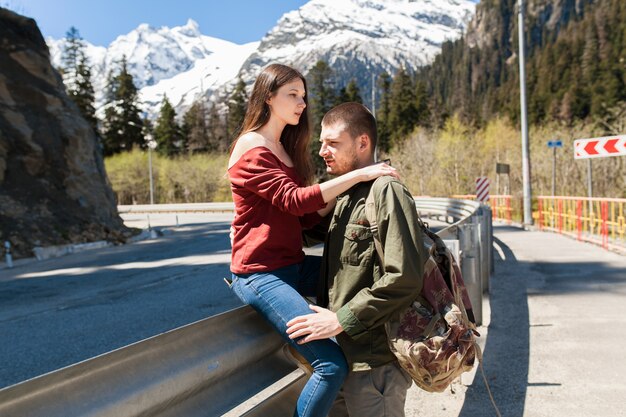 Joven hipster hermosa pareja de enamorados, sentado en la carretera