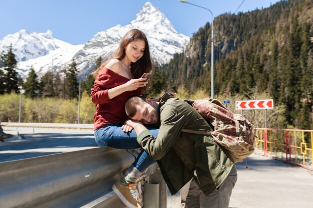 Joven hipster hermosa pareja de enamorados, sentado en la carretera