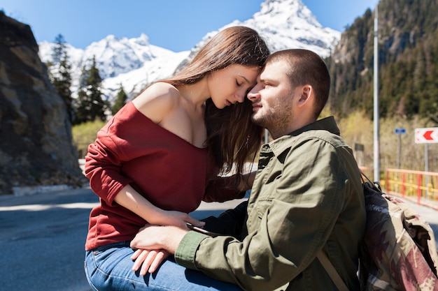 Joven hipster hermosa pareja de enamorados, sentado en la carretera