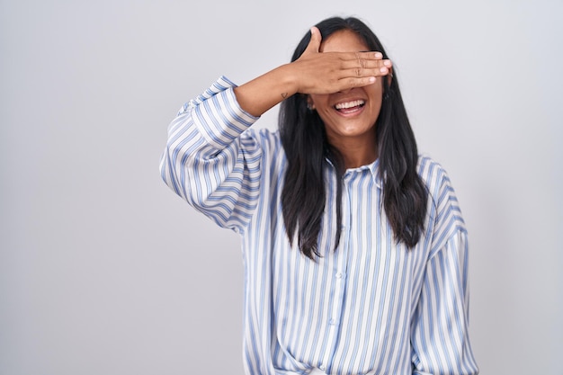 Foto gratuita joven hispana con gafas sonriendo y riendo con la mano en la cara cubriendo los ojos para sorprender el concepto ciego