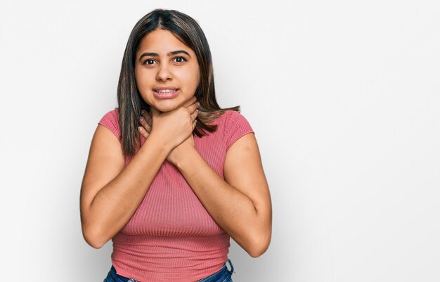 Joven hispana con pantalones casual gritando y asfixiándose por un doloroso estrangulamiento. problema de salud. concepto de asfixia y suicidio.