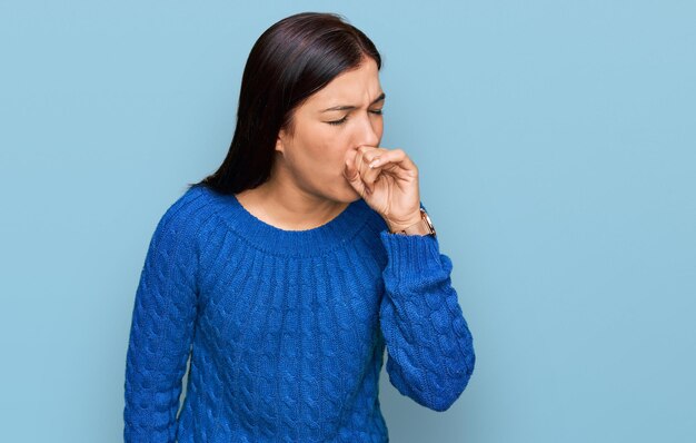 Joven hispana con ropa informal que se siente mal y tose como síntoma del resfriado o el concepto de atención médica con bronquitis