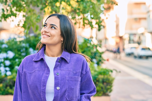 Joven hispana sonriendo feliz caminando en el parque