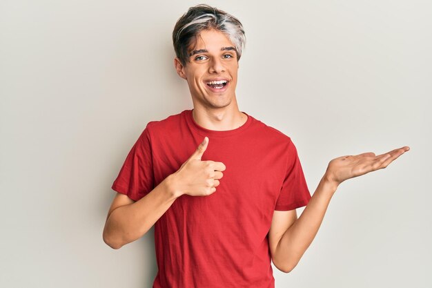 Joven hispano con ropa informal mostrando la mano de la palma y haciendo un gesto correcto con los pulgares hacia arriba sonriendo feliz y alegre