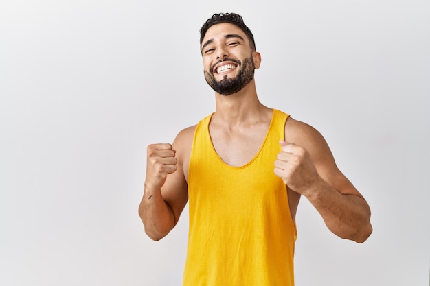 Foto gratuita joven hombre apuesto con barba sobre un fondo aislado muy feliz y emocionado haciendo gesto de ganador con los brazos levantados sonriendo y gritando por el concepto de celebración de éxito