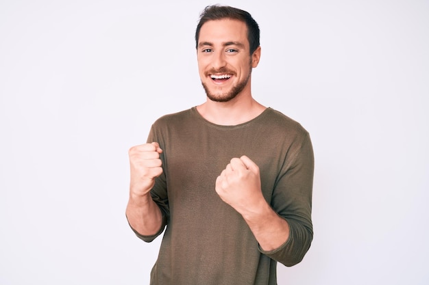 Joven hombre apuesto con ropa informal muy feliz y emocionado haciendo gesto de ganador con los brazos levantados, sonriendo y gritando por el éxito. concepto de celebración.