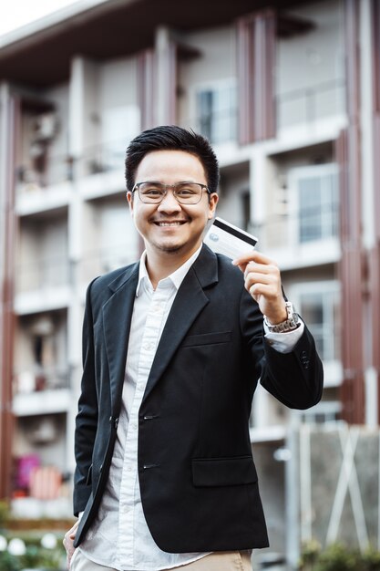 Joven hombre guapo disfrutar de compras en línea en el teléfono móvil con tarjeta de crédito.