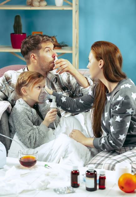 Foto gratuita la joven y el hombre con la hija enferma en casa. tratamiento en el hogar. luchando con una enfermedad. asistencia médica. debilidad familiar. el invierno, la gripe, la salud, el dolor, la paternidad, el concepto de relación