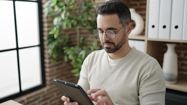 Foto gratuita joven hombre hispano trabajador de negocios usando touchpad trabajando en la oficina