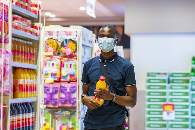 Joven hombre negro feliz de compras con una máscara médica