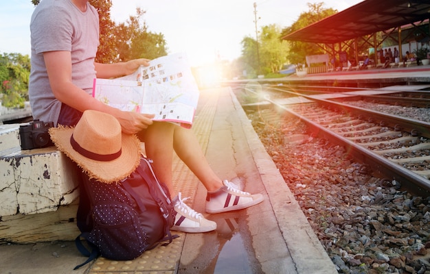 Joven hombre viajero con mochila y sombrero en la estación de tren con un viajero, viajes y concepto de recreación