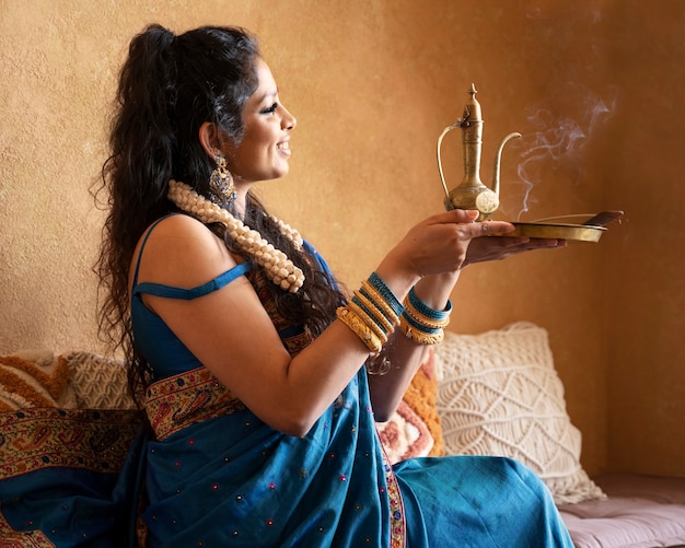 Joven india vistiendo sari y sosteniendo tetera