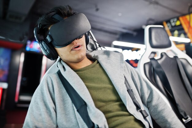 Joven indio divirtiéndose con una nueva tecnología de auriculares vr en un simulador de realidad virtual