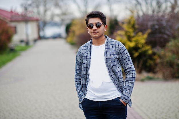 Un joven indio elegante con gafas de sol usa una pose informal al aire libre