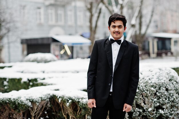 Joven indio con traje y corbata de moño posó al aire libre en un día de invierno