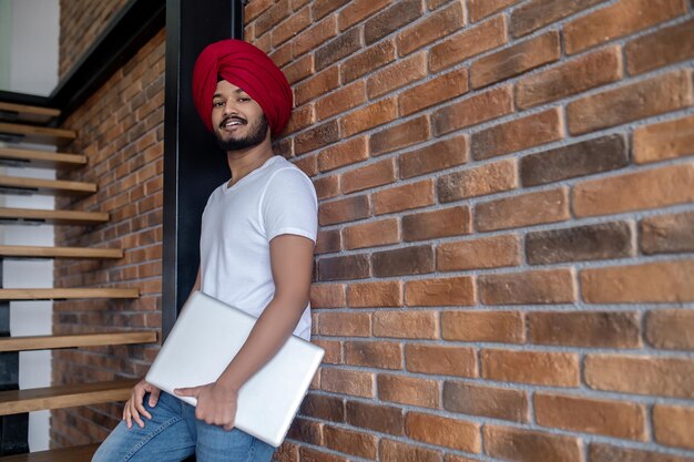 Joven indio con turbante rojo parado en las escaleras