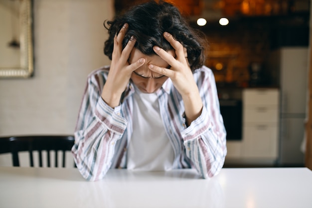 Foto gratuita joven infeliz frustrado con mirada deprimida, mirando hacia abajo, con las manos en la cabeza, estresado con problemas financieros porque fue despedido.