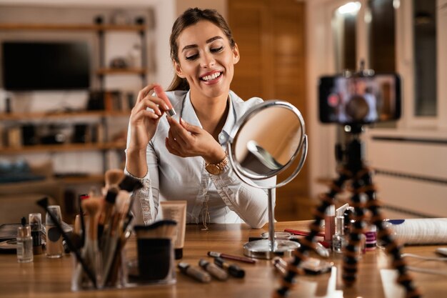 Joven influencer sosteniendo bálsamo labial mientras vloguea sobre maquillaje en casa