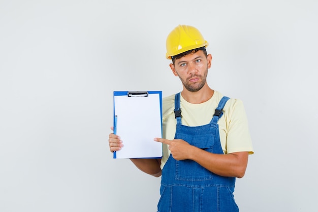 Foto gratuita joven ingeniero apuntando al portapapeles en vista frontal uniforme.