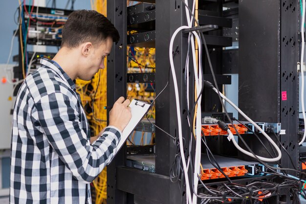 Joven ingeniero escribiendo en portapapeles tiro medio