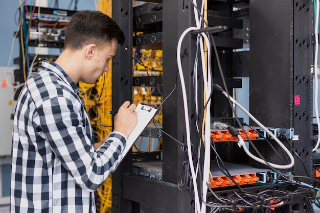 Joven ingeniero escribiendo en portapapeles tiro medio