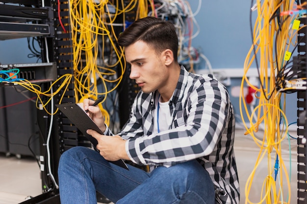 Foto gratuita joven ingeniero escribiendo en portapapeles