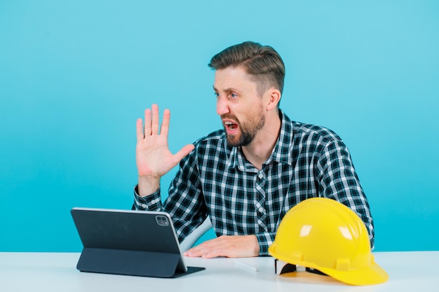 El joven ingeniero grita levantando la mano con el fondo azul